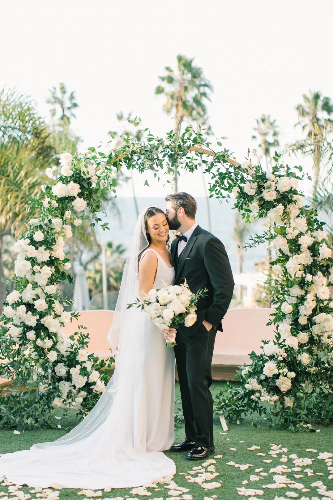 newlywed couple at ceremony with soft white wedding florals